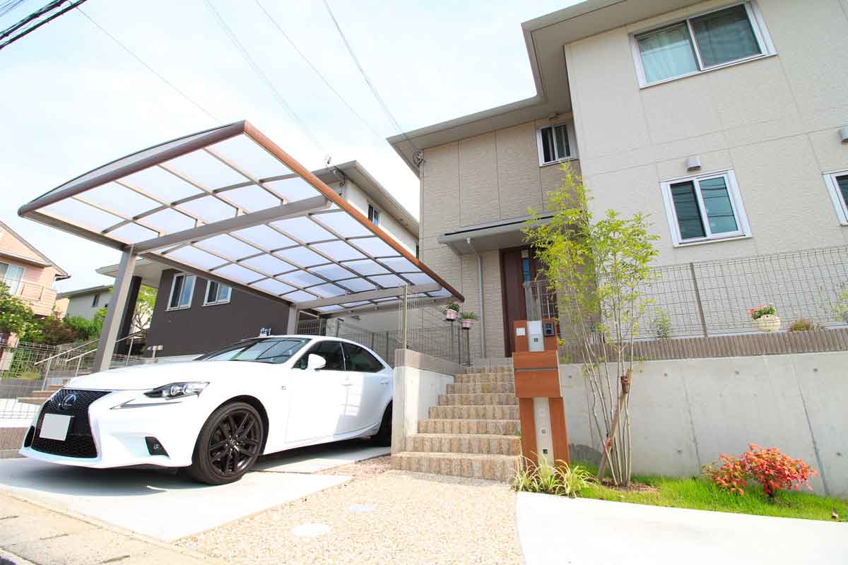 automobile parcheggiata sotto un carport per auto, la tettoia è trasparente e le finiture sono in alluminio color legno